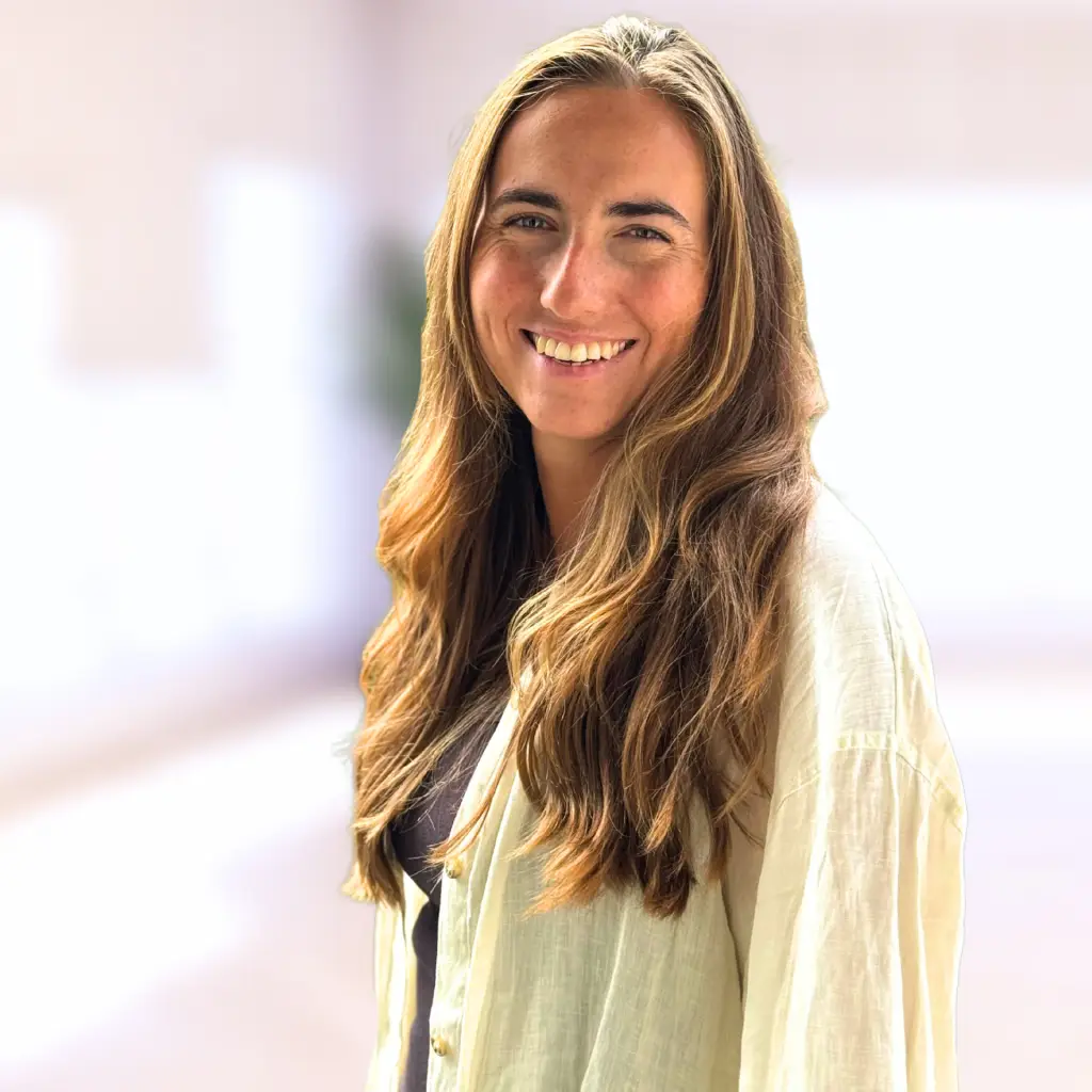 Portrait der Teamassistenz Luise Gerber beim gründungs.center. Das Portrait einer jungen Frau mit langen braunen, gewellten Haaren, die offen über ihre Schulter in die Kamera lacht.