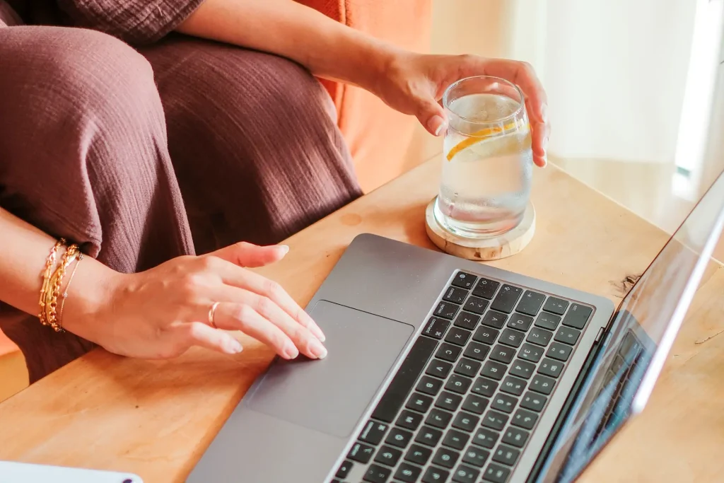 Sinnbild: Gründen aus der Kündigung. Eine junge Frau sitzt an einem Couchtisch und tippt auf einem Laptop
